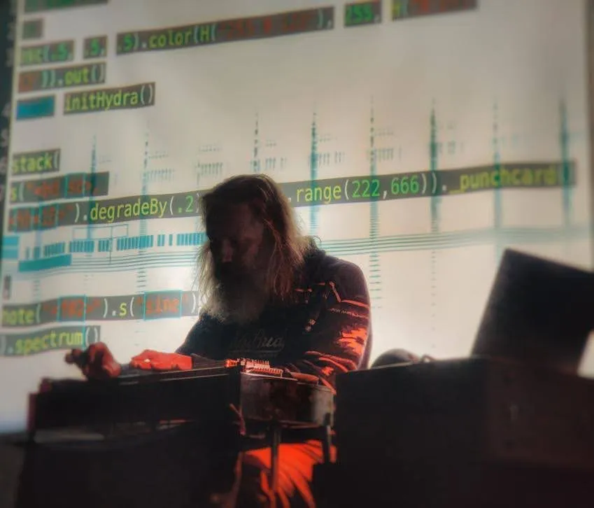 Randy Brown playing pedal steel in silhouette against projected Strudel code